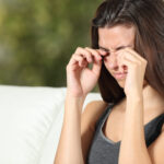 Young woman rubbing her eyes sitting on a couch