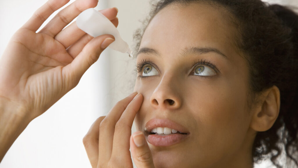 Young woman putting eye drops in her eyes