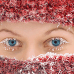 Woman with red hat and scarf looking at camera with ice crystals on her face