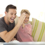 man and boy giving a high 5 while sitting on couch