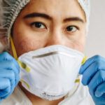 Man with gloves putting on mask