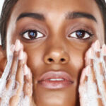 Black woman looking at camera with soapy hands on her cheeks