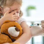Child with teddy bear getting a shot