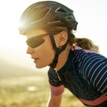 Young woman in helmet and glasses cycling outdoors