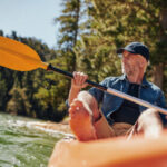 man rowing in orange boat on river