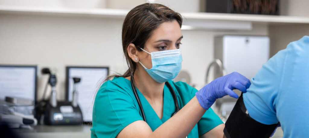 Female medical assistant placing blood pressure cuff on patient