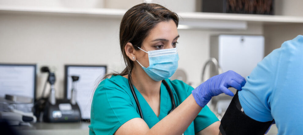 Female medical assistant placing blood pressure cuff on patient