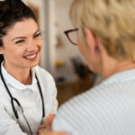 female healthcare provider touching the arm of a patient and smiling