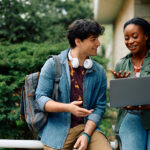 Two college-aged people outdoors with laptop